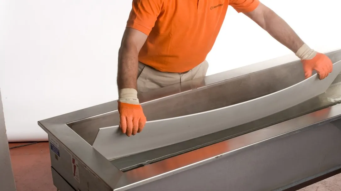 Worker bending a quartz slab using heat and water during the fabrication process.