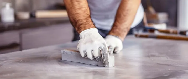 Ouvrier polissant un comptoir en quartz Caesarstone avec des gants de protection.